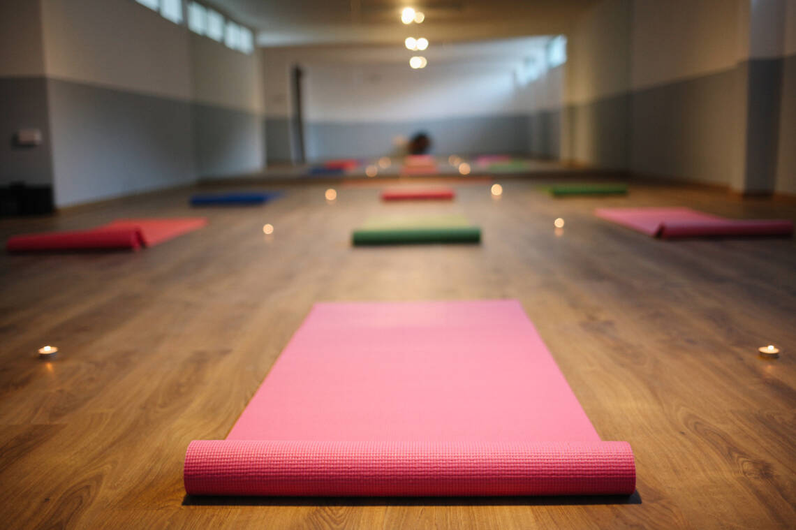 Yogamatte in Raum mit Holzboden, Kerzen auf dem Boden