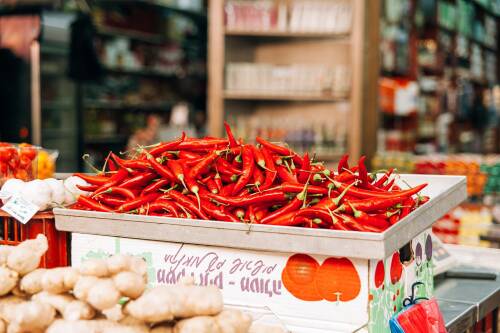 Chilischoten dürfen in mexikanischem Essen nicht fehlen. Rote Chilischoten ausgebreitet auf einem Markt, von der Seite fotografiert.