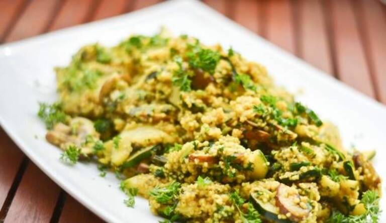 Couscous auf weißem Teller mit Zucchini, Champignons und Curry