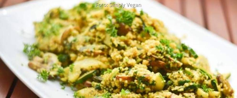 Couscous auf weißem Teller mit Zucchini, Champignons und Curry