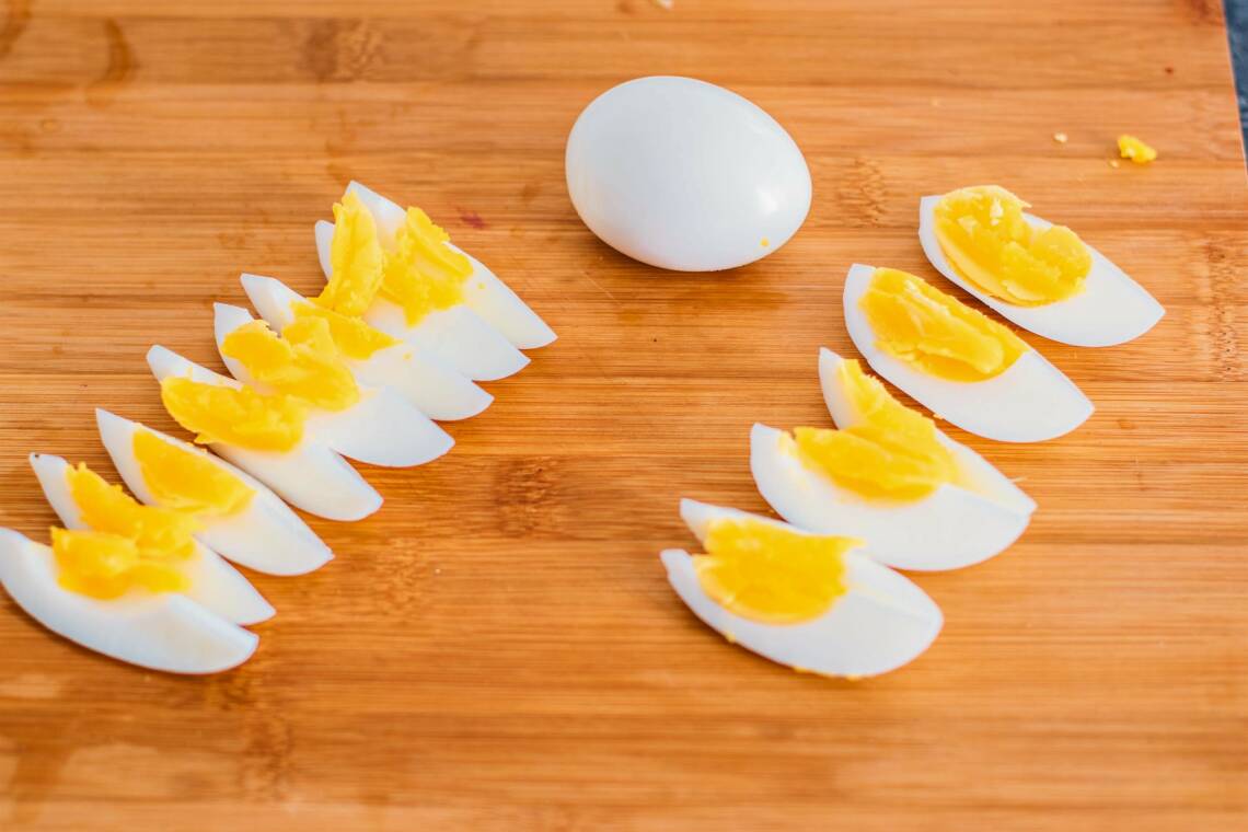 Aufgeschnittene Eier und ganzes Ei auf Schneidebrett.
