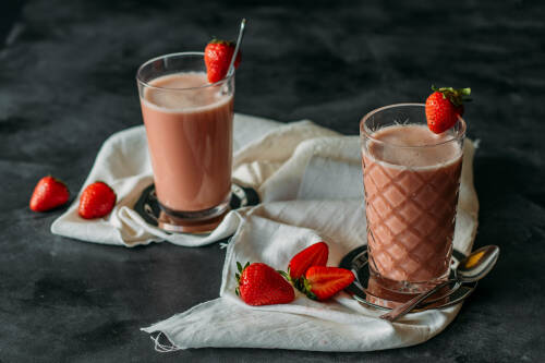 Erdbeer Smoothie in Gläsern vor dunklem Hintergrund.