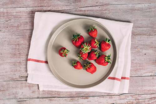 Erdbeeren auf weißem Teller vor hellem Hintergrund.