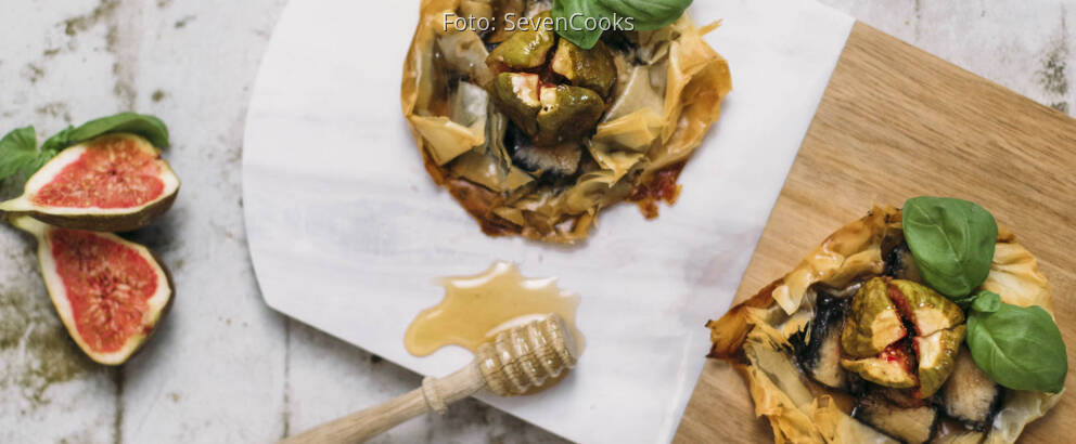 Zwei Asche Käse Tarteletts auf einem Brett mit Honig und Feigen