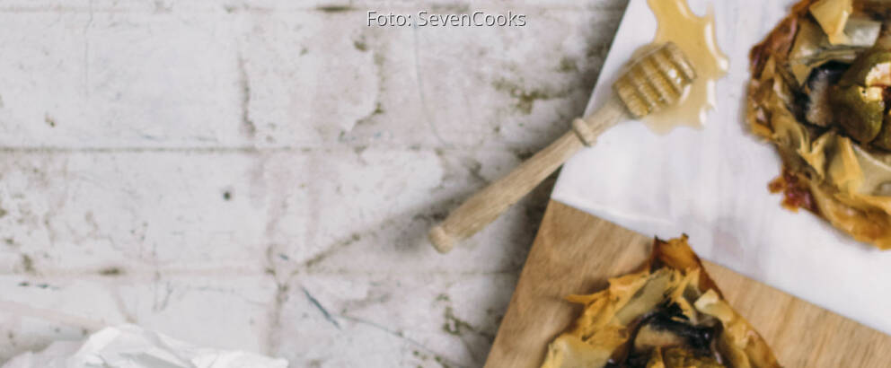 Zwei Asche Käse Tarteletts auf einem Brett mit Honig und Feigen