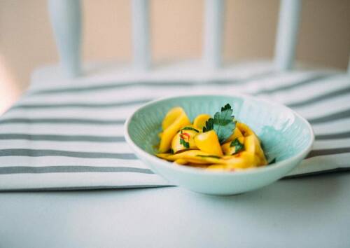 Salat aus frischer Mango mit einem Kick Chili. Saftiges Gelb in blauer Schüssel, von oben fotografiert.