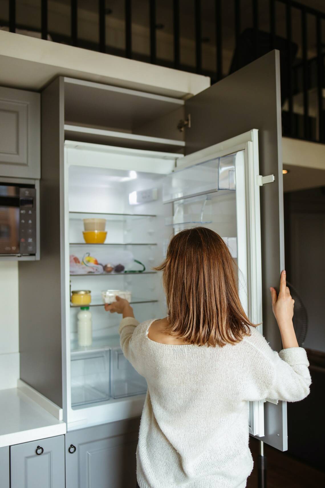 Frau vor Kühlschrank öffnet Türe