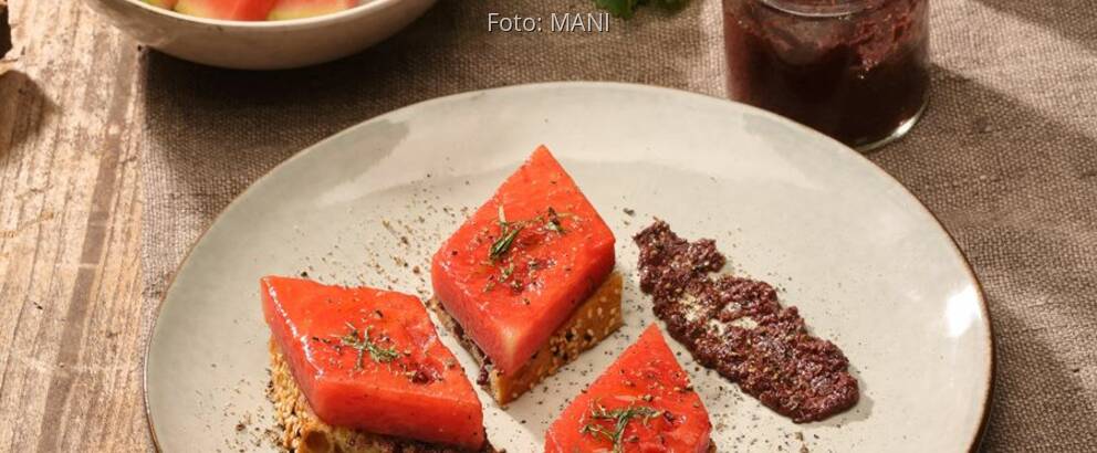 Teller mit gebratener Wassermelone, Olivnepaste auf Holztisch