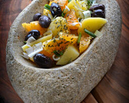 Steinschale mit Salat aus Kartoffeln, Oliven, Zwiebeln, Orange, Kapern