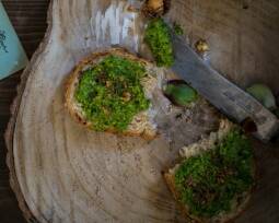 Holzscheibe mit zwei Brotscheiben mit Grünkohlpesto und Messer