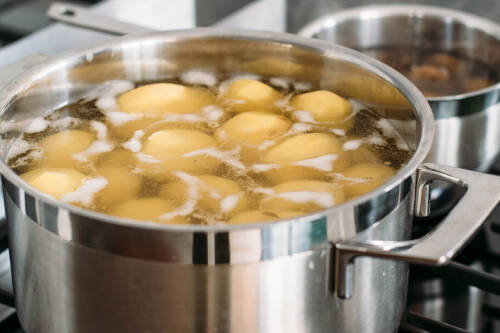 Beim Kochen von Kartoffeln bildet sich oftmals Schaum an der Wasseroberfläche. Dies ist jedoch nur austretendes Eiweiß. Von der Seite fotografiert.