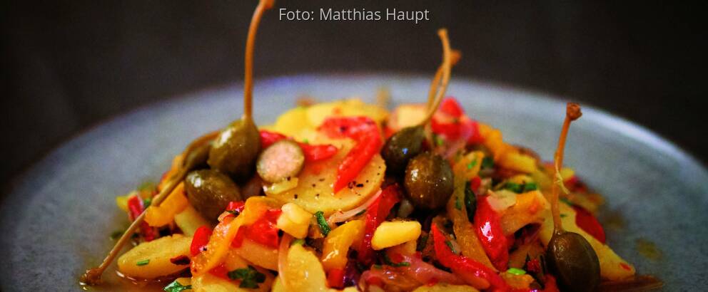 Kartoffelsalat mit Paprika und Kapern auf einem Teller