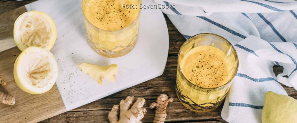 Draufsicht auf gelben Kurkuma-Ingwer Immunbooster in zwei Gläsern mit Strohhalm.