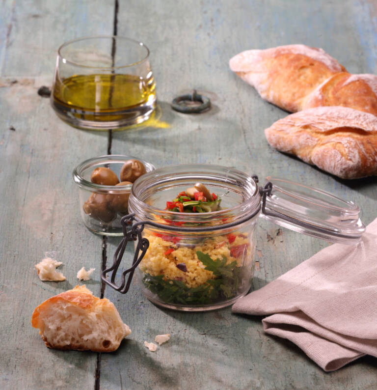 Glas mit Maistaboulet mit Olivenöl, Fladenbrot auf Holztisch