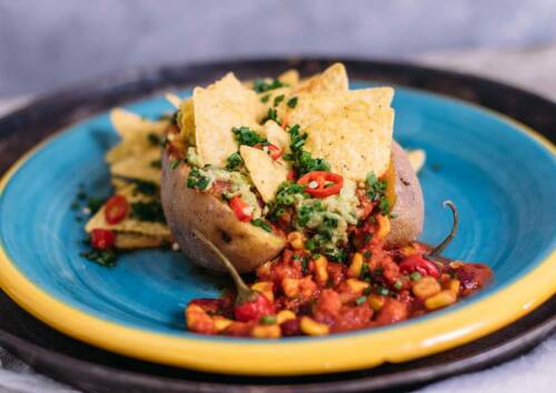 Mexikanische Geschmacksexplosion in Form einer gefüllten Ofenkartoffel – mit pflanzlichem Eiweiß, das satt macht. Auf einem Teller von vorne fotografiert.