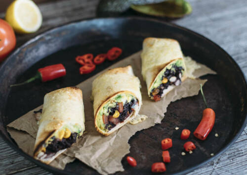 Wenn man mexikanisch Essen will, dann gehören Burritos einfach dazu. Diese hier sind sogar mit Käse überbacken. Drei Stück auf einem Tablett, von oben fotografiert.