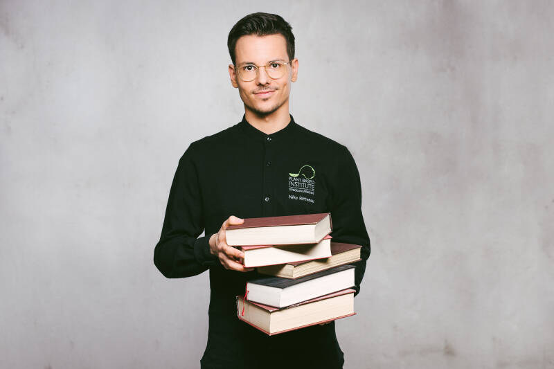 Buchautor und Ernährungsberater Niko Rittenau mit Bücher in der Hand. Portait von vorne.