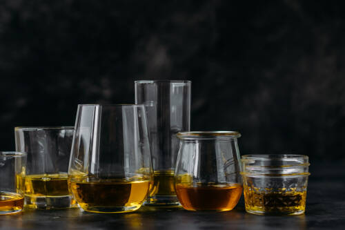 Verschiedene Öle in Gläsern vor dunklem Hintergrund.