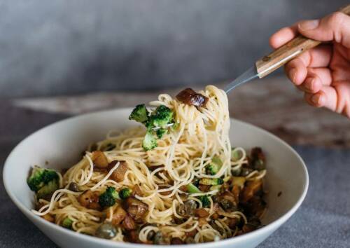 Spaghetti mit Brokkoli und gehackten Maronen in einer Schüssel, von oben-seitlich fotografiert.