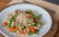 Teller mit Penne, Pucola, frischen Tomaten und veganem Parmesan