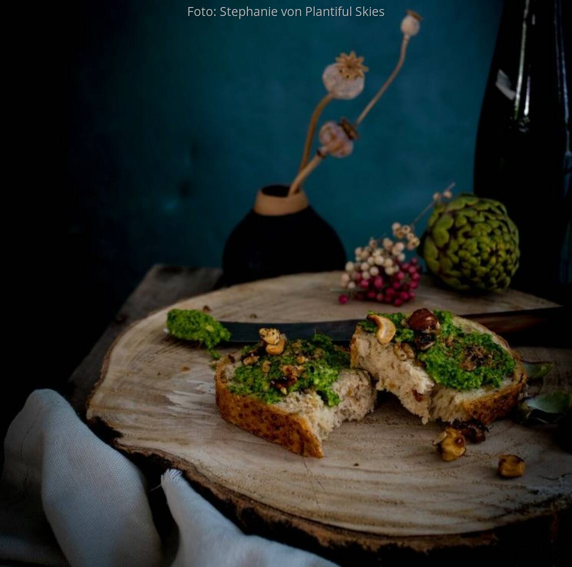 Grünkohl-Pesto auf Baguette liegt auf einer Holzscheibe mit Deko