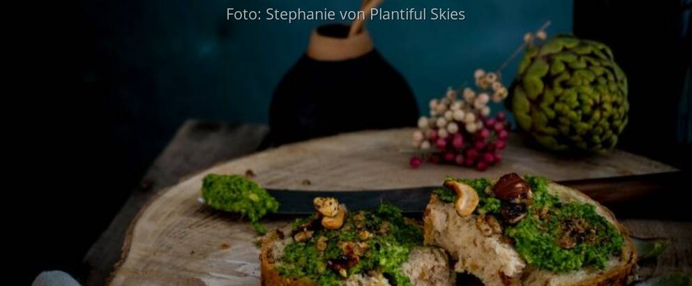 Grünkohl-Pesto auf Baguette liegt auf einer Holzscheibe mit Deko