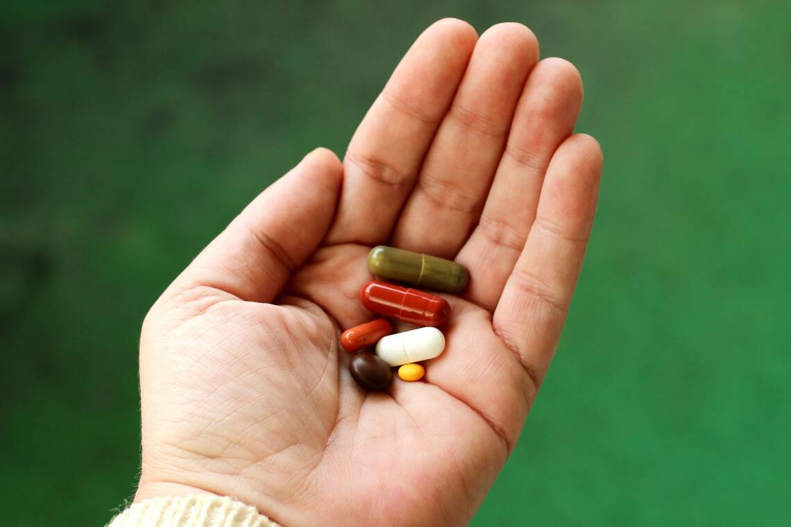 Stoffwechsel ankurbeln: Auf einer Handfläche liegen verschiedenfarbige Pillen