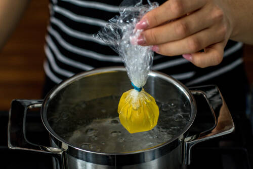 Das Ei in dem Päckchen aus Frischhaltefolie kannst du nun in einen Topf mit kochendem Wasser geben.