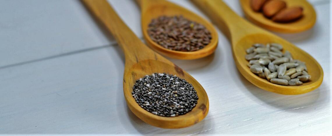 Verschiedene Samen in Holzlöffeln: Quinoa, Leinsamen
