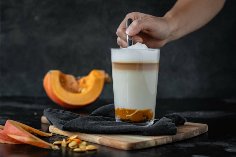 Pumpkin Spice Latte in einem Glas - wird umgerührt.