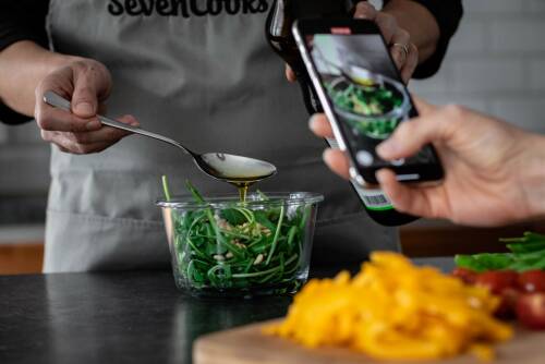 Rucola Salat in einer Schüssel welcher durch eine Person mit einem Handy fotografiert wird