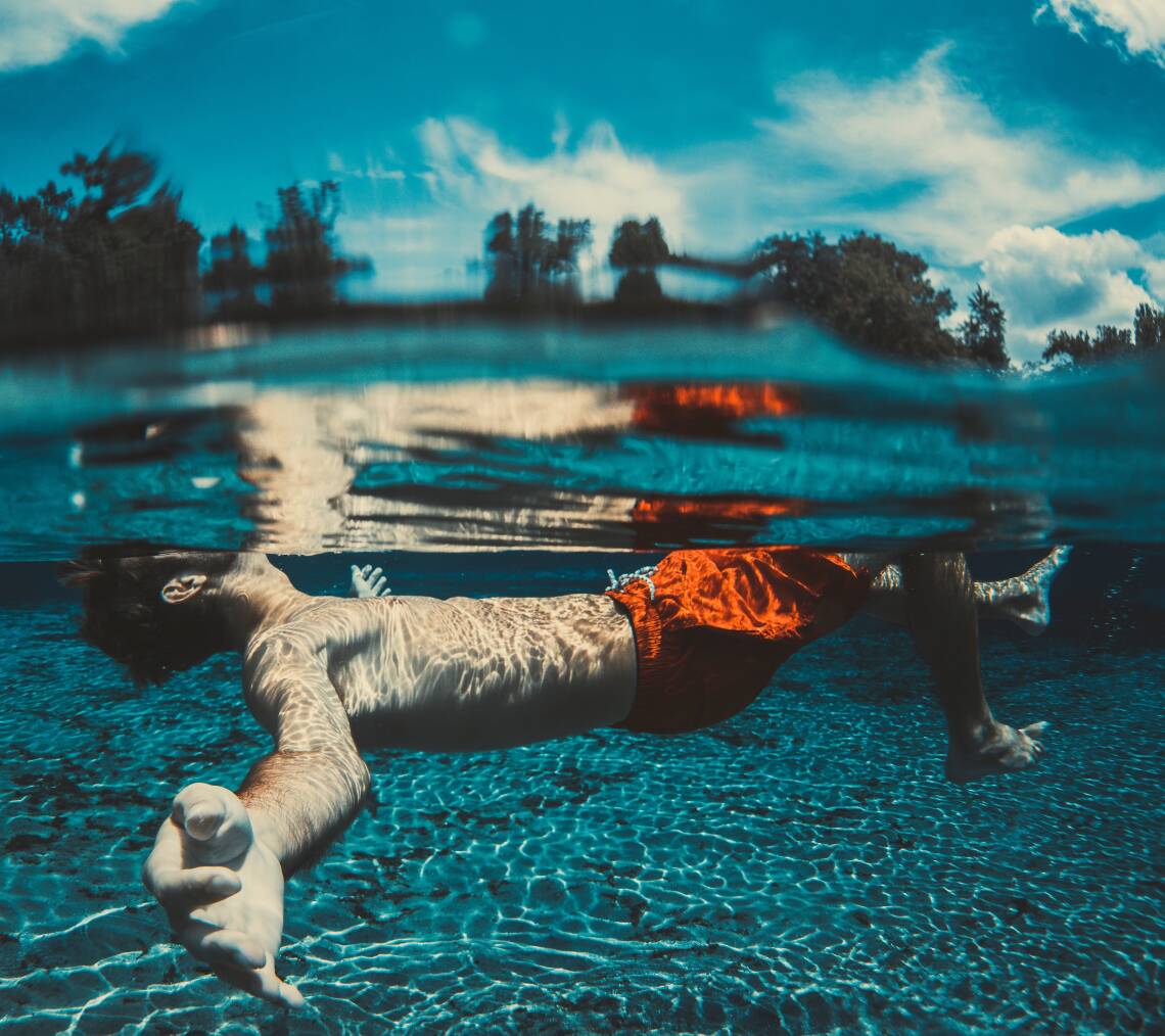 Junger Mann taucht im blauen Wasser