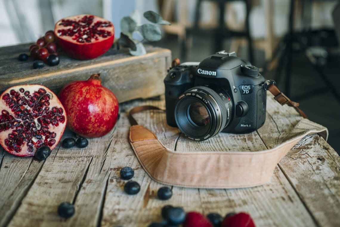 Kamera und Granatapfel halbiert auf einem Holzbrett