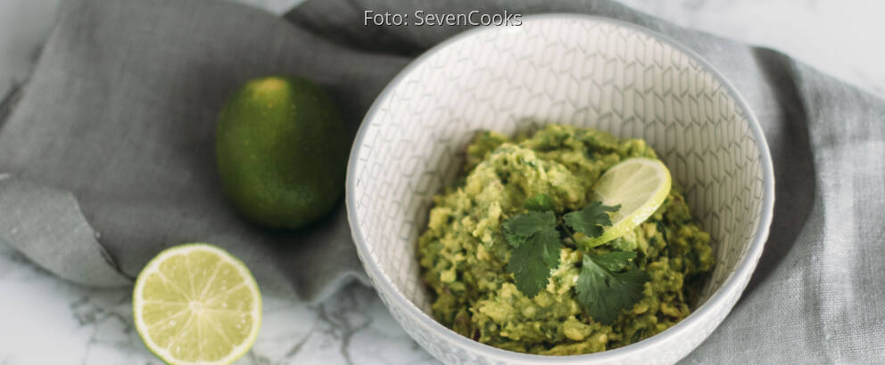 Veganes Rezept: Guacamole mit aufgeschnittener Limette in Schüssel angerichtet