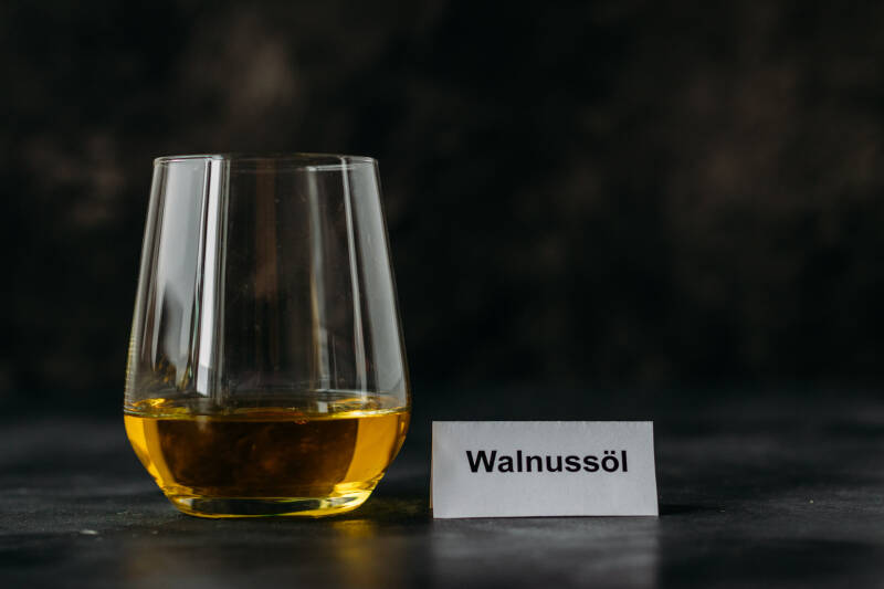 Walnussöl in Glas vor dunklem Hintergrund.