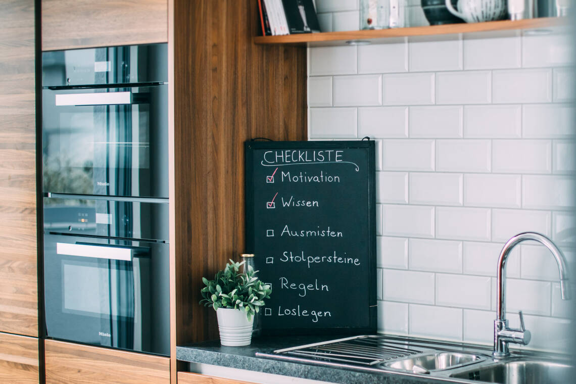 Schwarze Tafel mit Checkliste steht vor weiß gekachelter Wand in einer Küche | Foto: SevenCooks