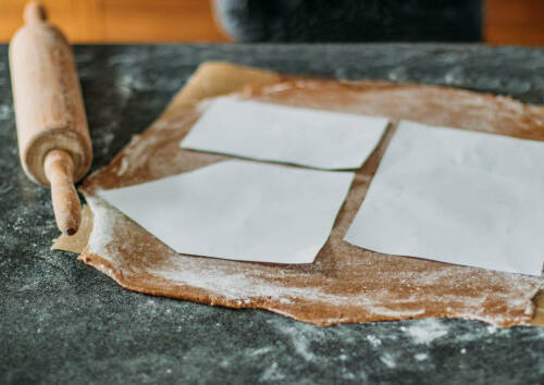 Teig Lebkuchen ausgerollt mit Schablonen aus Papier für ein Lebkuchenhaus