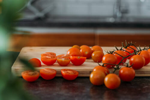 Zubereitung_Schritt_1:_halbierte_Cocktailtomaten_auf_Holzbrett Zubereitung: halbierte Cocktailtomaten auf Holzbrett für Baked Feta Pasta